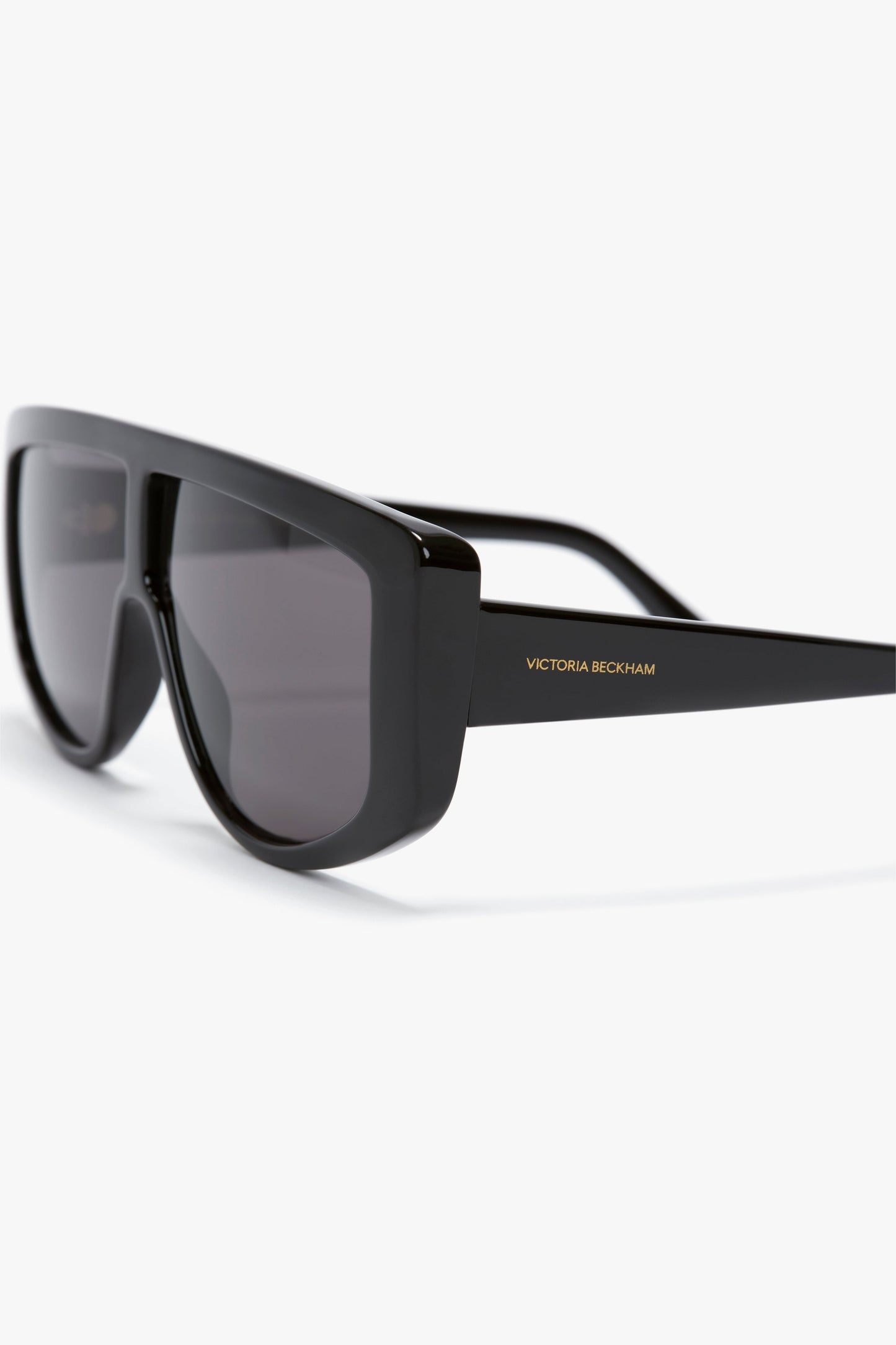 A pair of Acetate Visor Sunglasses In Black with black tonal lenses and the brand name "Victoria Beckham" written on the arm.
