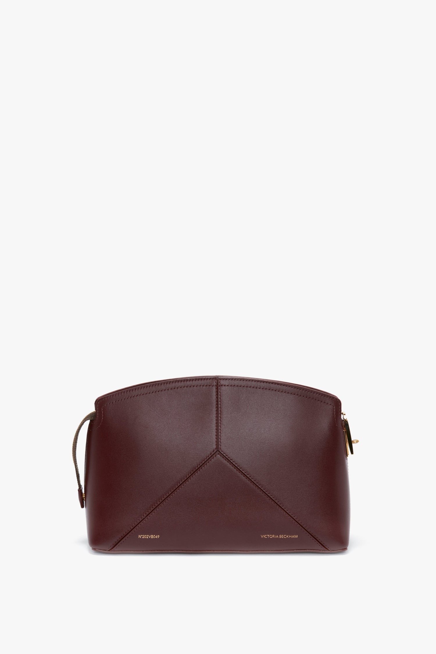 A Victoria Beckham Victoria Clutch Bag In Burgundy Leather with a geometric seam design and a small gold clasp. The bag has a strap on the side and "Victoria Beckham" is embossed in gold at the bottom, making it a stylish clutch bag for any occasion.