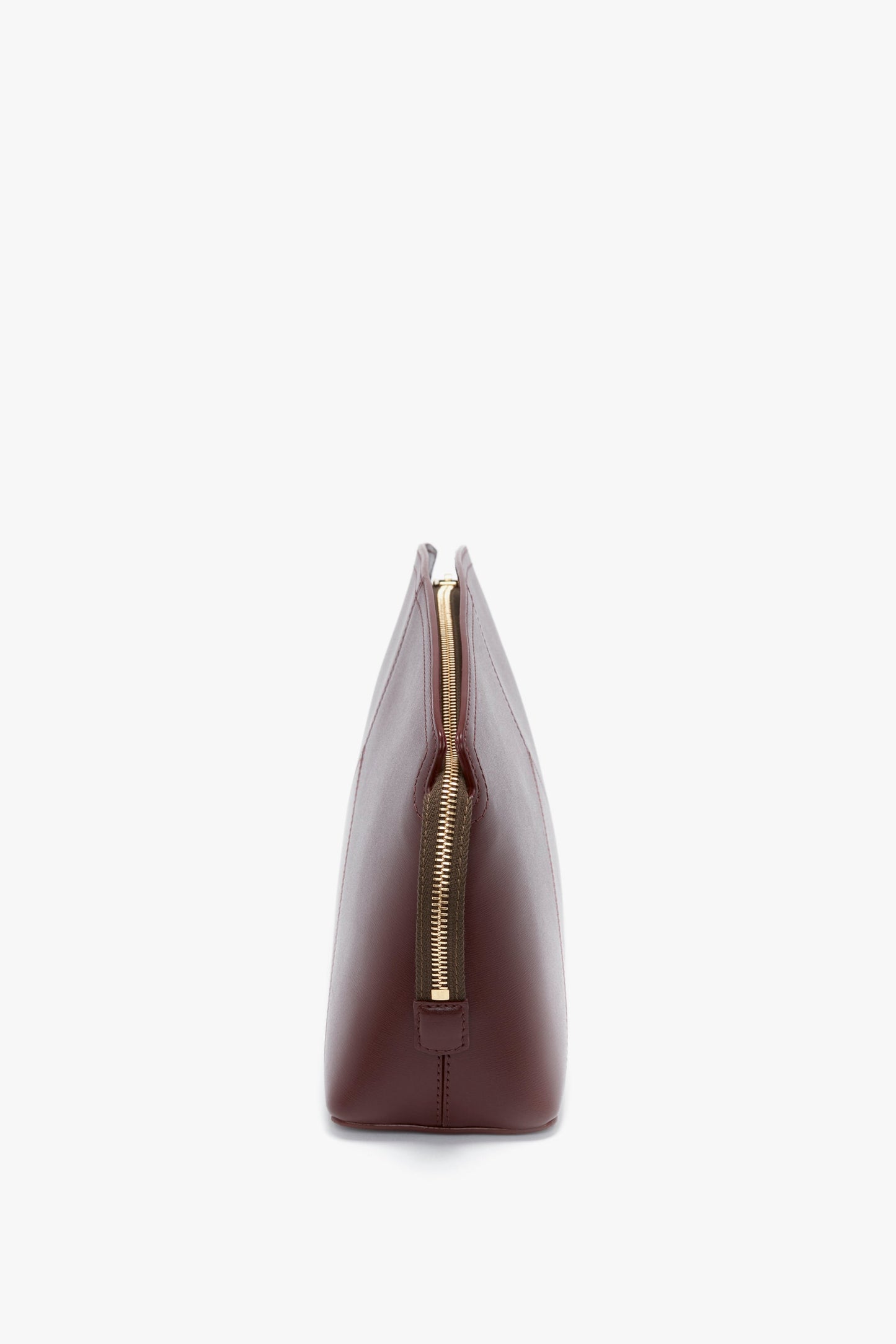 Side view of a Victoria Beckham Victoria Clutch Bag in rich burgundy leather with a central gold zipper, shown against a plain white background.