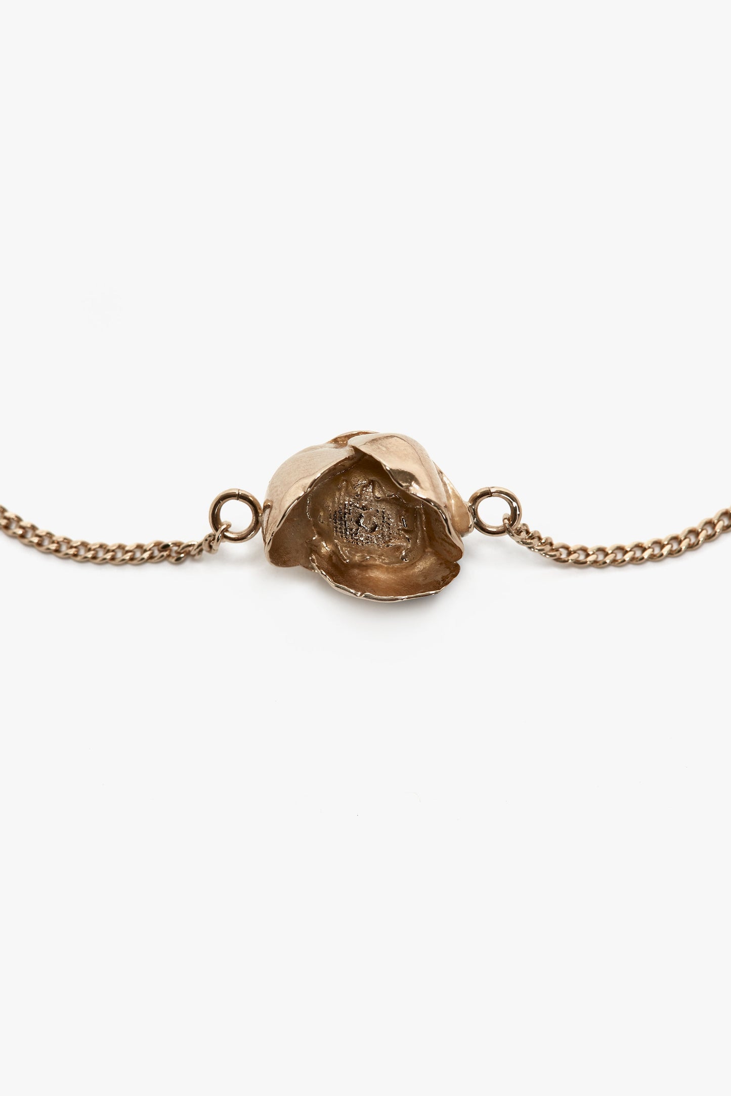 Close-up of an Exclusive Camellia Flower Bracelet In Gold by Victoria Beckham featuring a realistic, detailed rose charm in the center. The charm connects to delicate, adjustable chain links on either side.