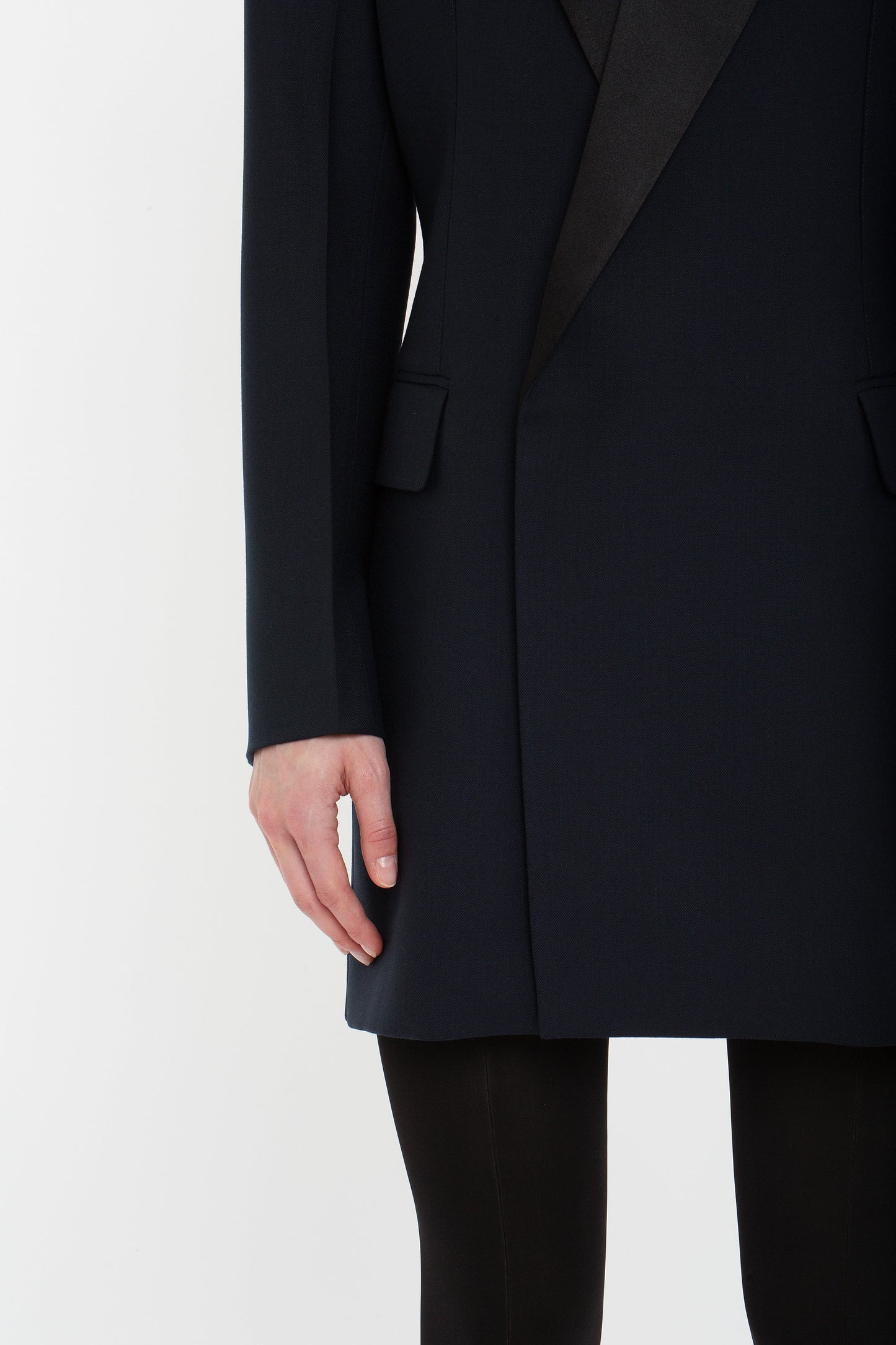 A person is shown from the shoulders down wearing an Exclusive Fold Shoulder Detail Dress In Midnight by Victoria Beckham. The person's left arm is relaxed by their side.