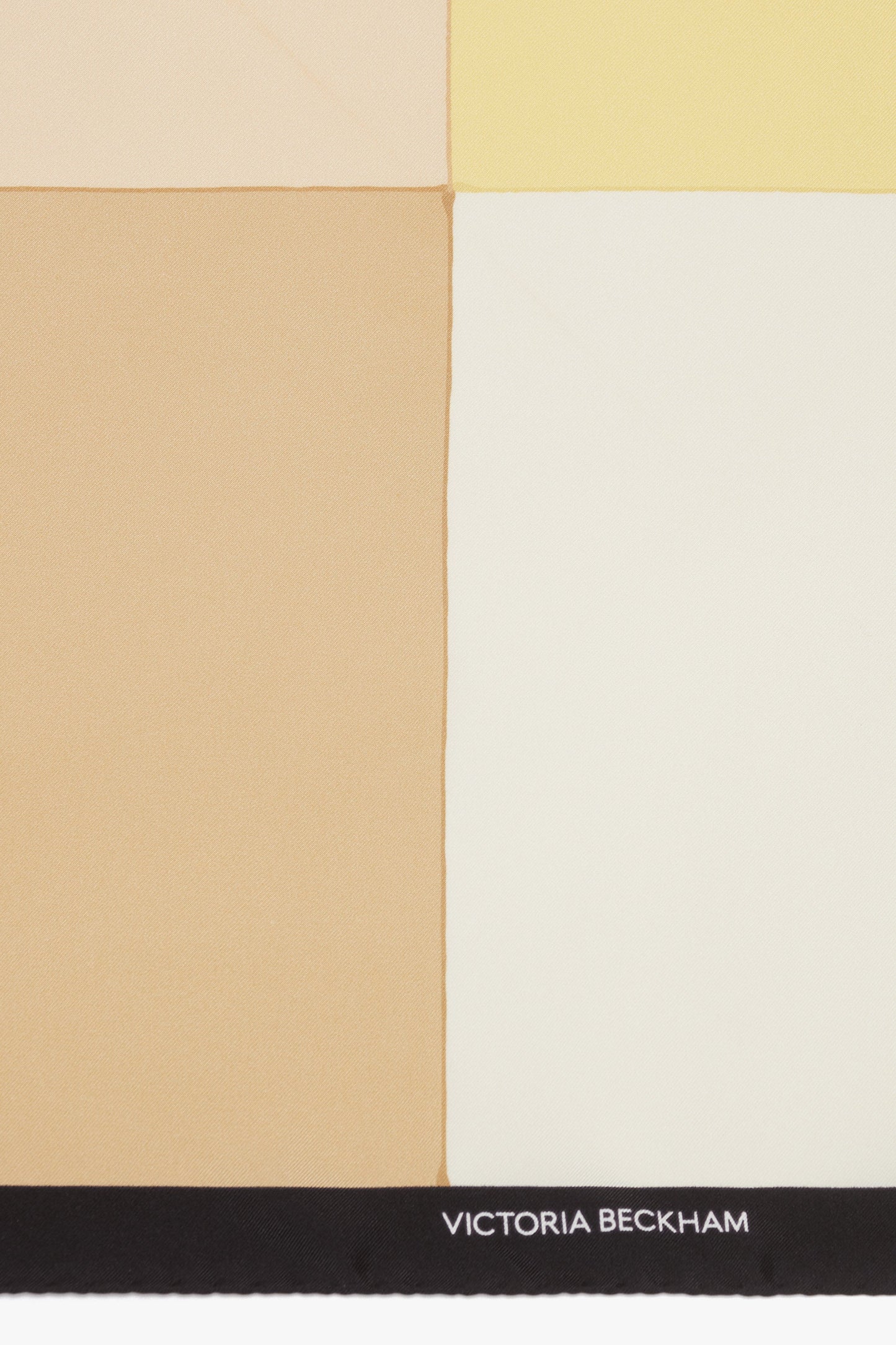 Abstract geometric design with shades of beige, yellow, and cream on luxurious Colour Block Foulard In Macadamia, segmented into quadrants with a black border at the bottom featuring the text "Victoria Beckham.