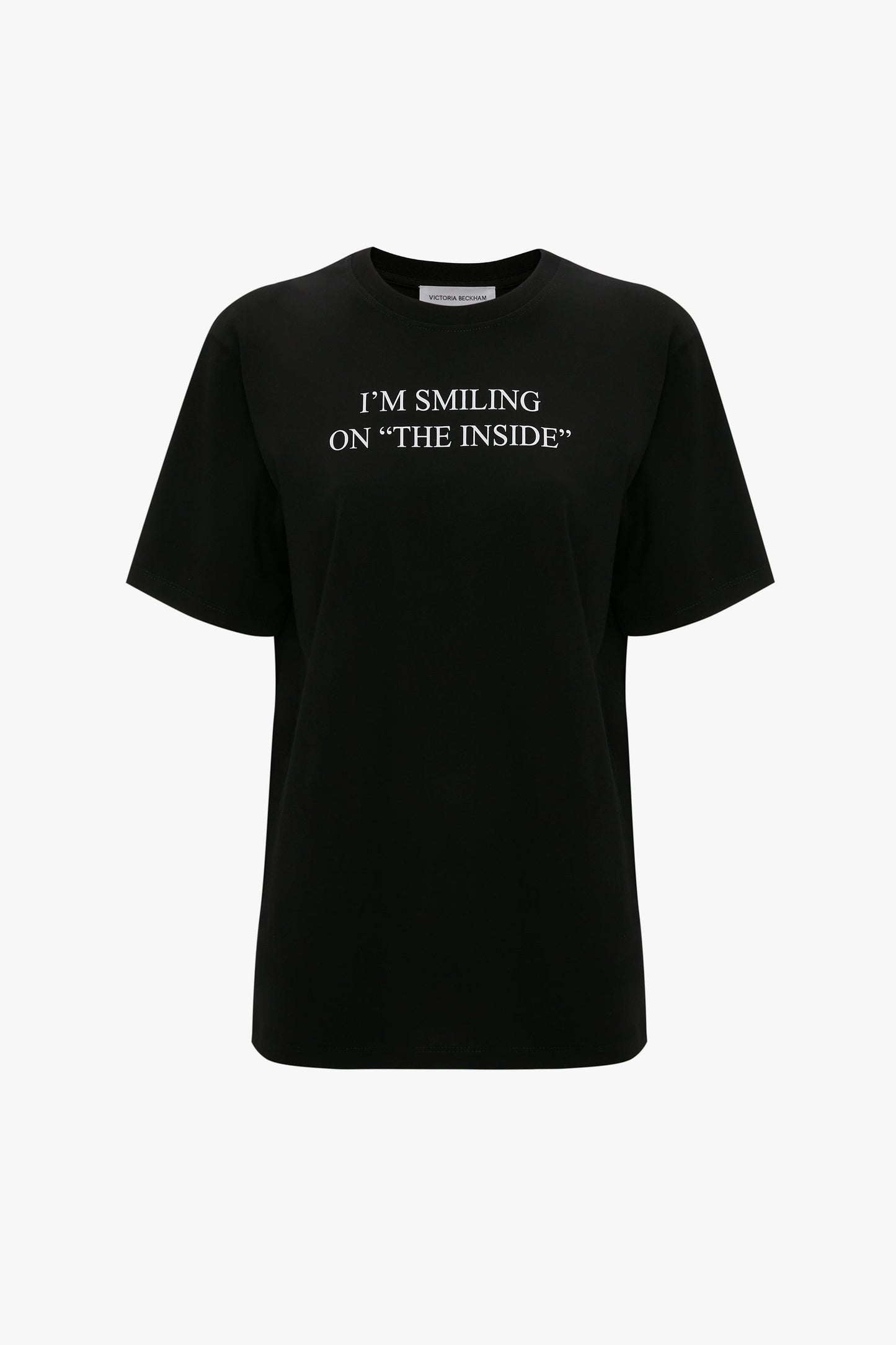 A relaxed fit, black slogan T-shirt made from organic cotton with "I'M SMILING ON 'THE INSIDE'" printed in white on the front. The I'm Smiling On The Inside Slogan T-Shirt in Black by Victoria Beckham.