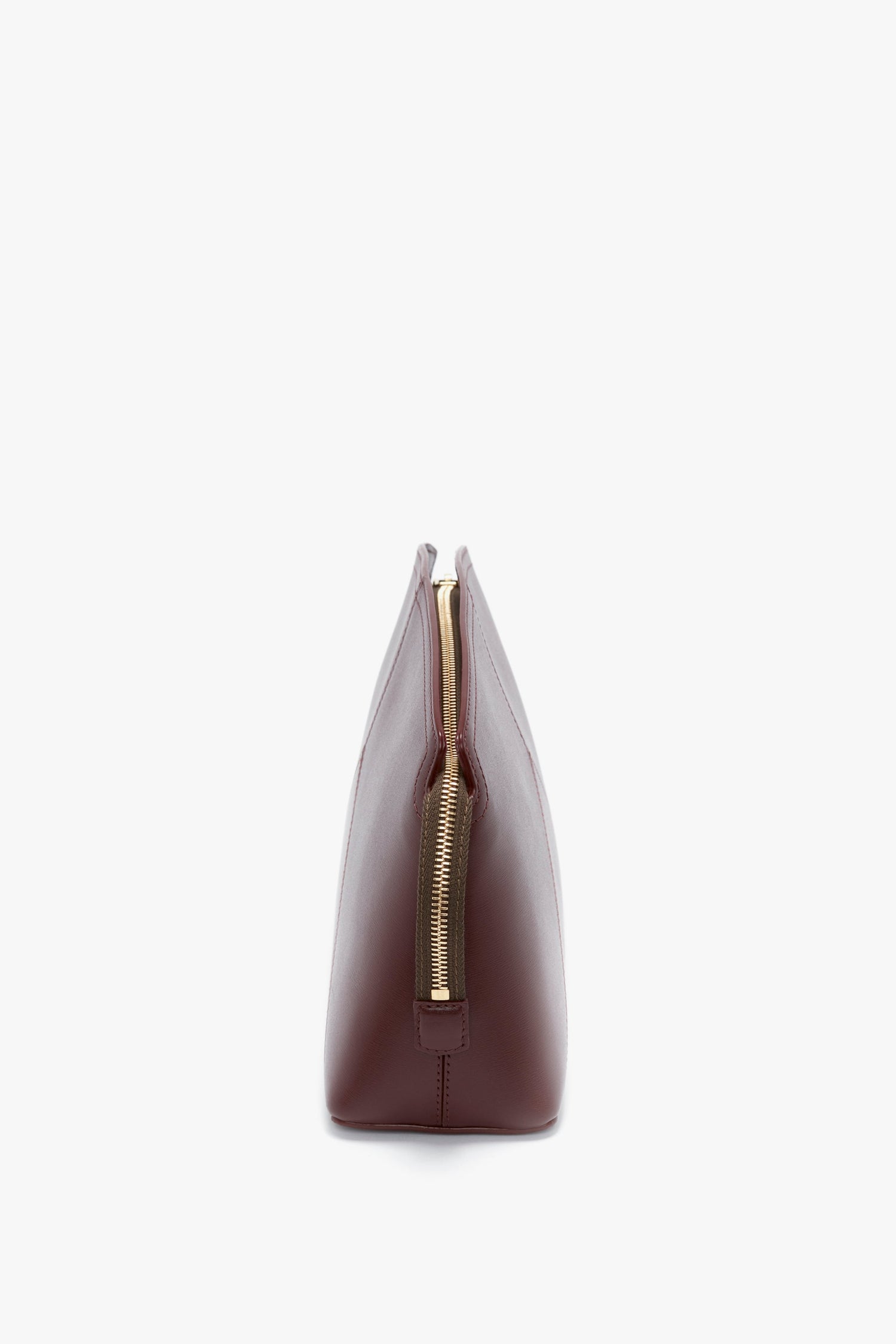 Side view of a Victoria Beckham Victoria Clutch Bag in rich burgundy leather with a central gold zipper, shown against a plain white background.