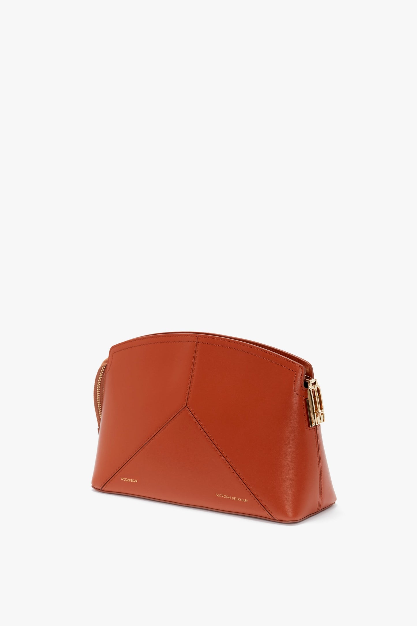 A Victoria Clutch Bag In Tan Leather with a geometric design, crafted from glossy calf leather, featuring a gold-toned buckle on the side and the brand name Victoria Beckham embossed at the bottom front.