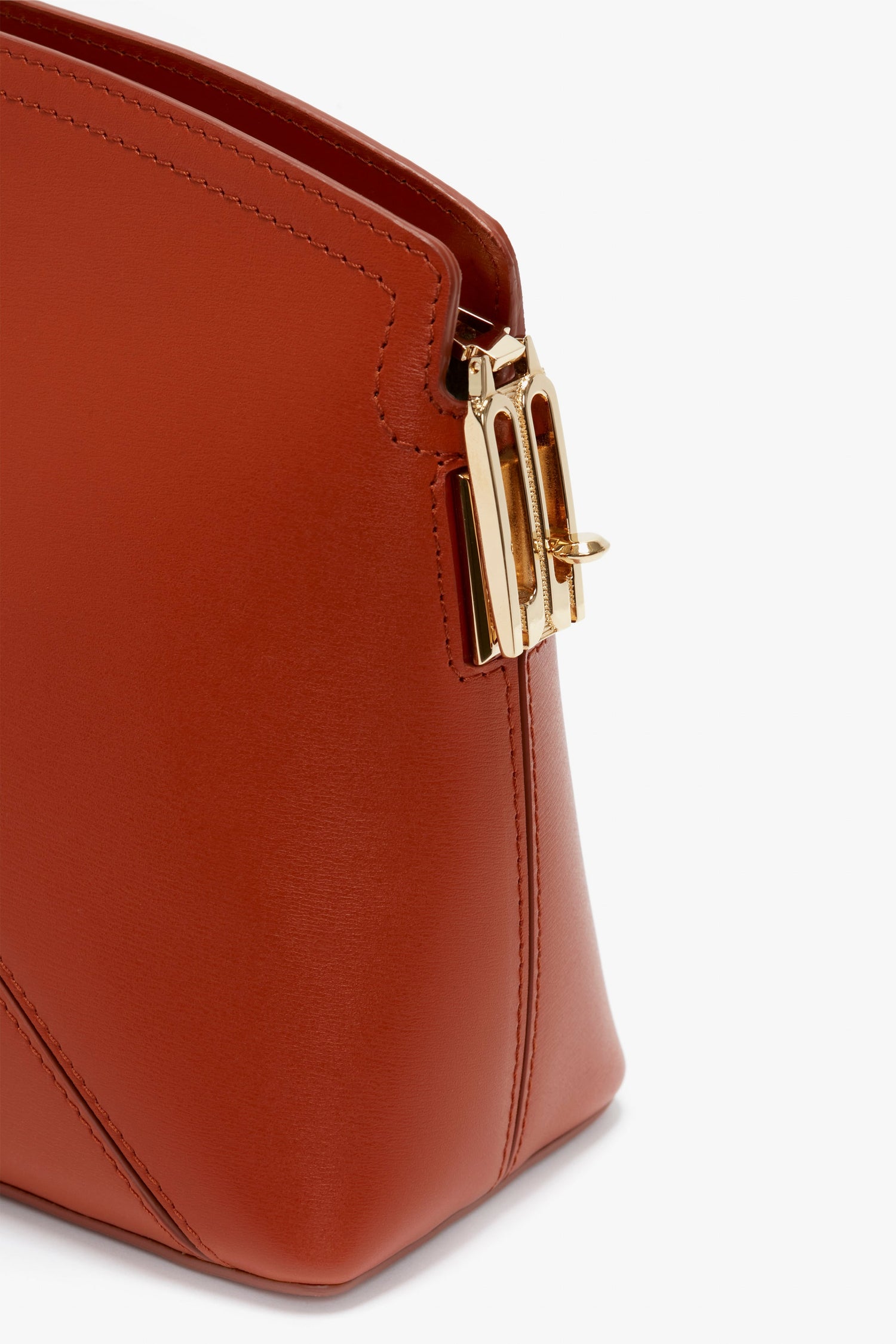 Close-up of a Victoria Beckham Victoria Clutch Bag In Tan Leather, featuring a gold rectangular buckle on the side.