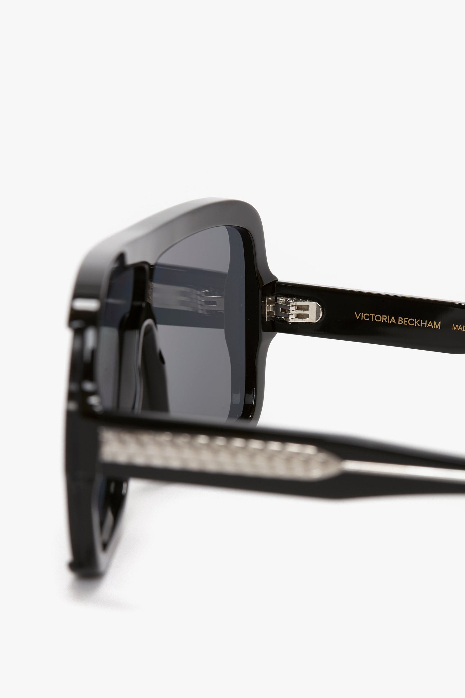 Close-up of black Victoria Beckham Layered Mask Sunglasses In Black-Silver-Mirror, showcasing the rectangular shape and acetate temples featuring the brand's logo and guilloch pattern design details.