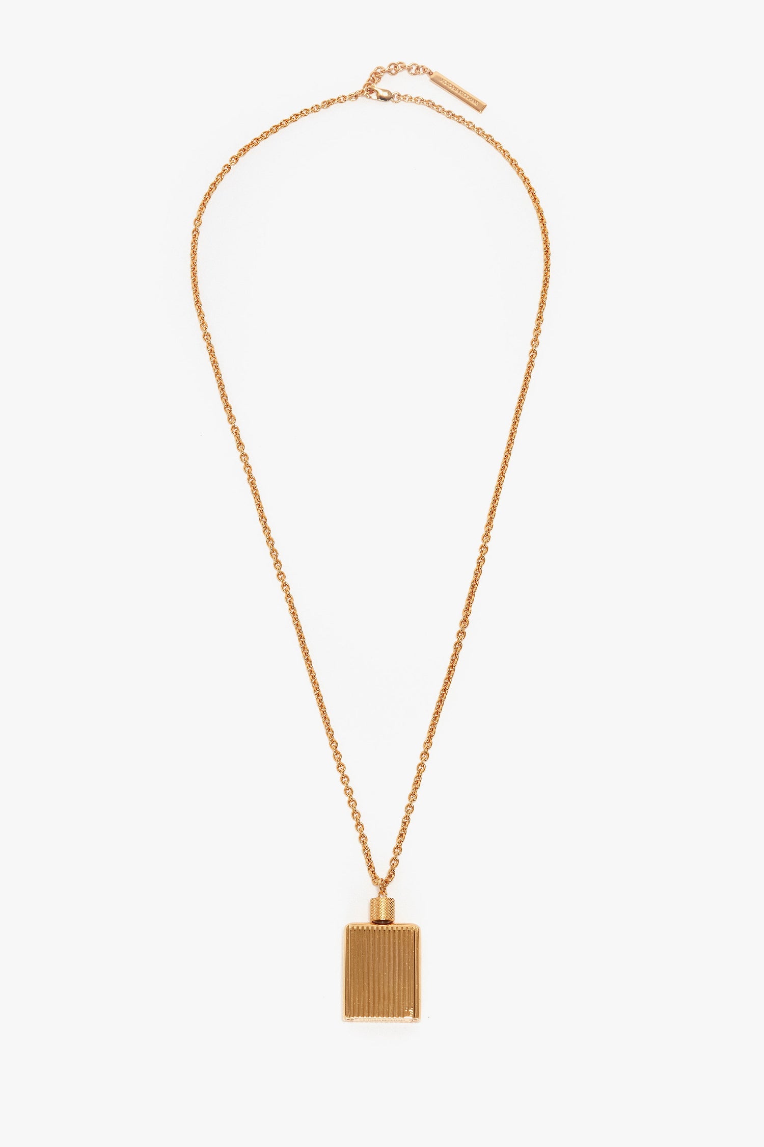 A gold necklace with a rectangular, gold brushed brass pendant featuring vertical grooves, reminiscent of the Victoria Beckham Exclusive Perfume Bottle Necklace In Brushed Gold.