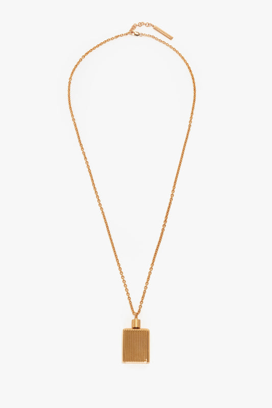 A gold necklace with a rectangular, gold brushed brass pendant featuring vertical grooves, reminiscent of the Victoria Beckham Exclusive Perfume Bottle Necklace In Brushed Gold.