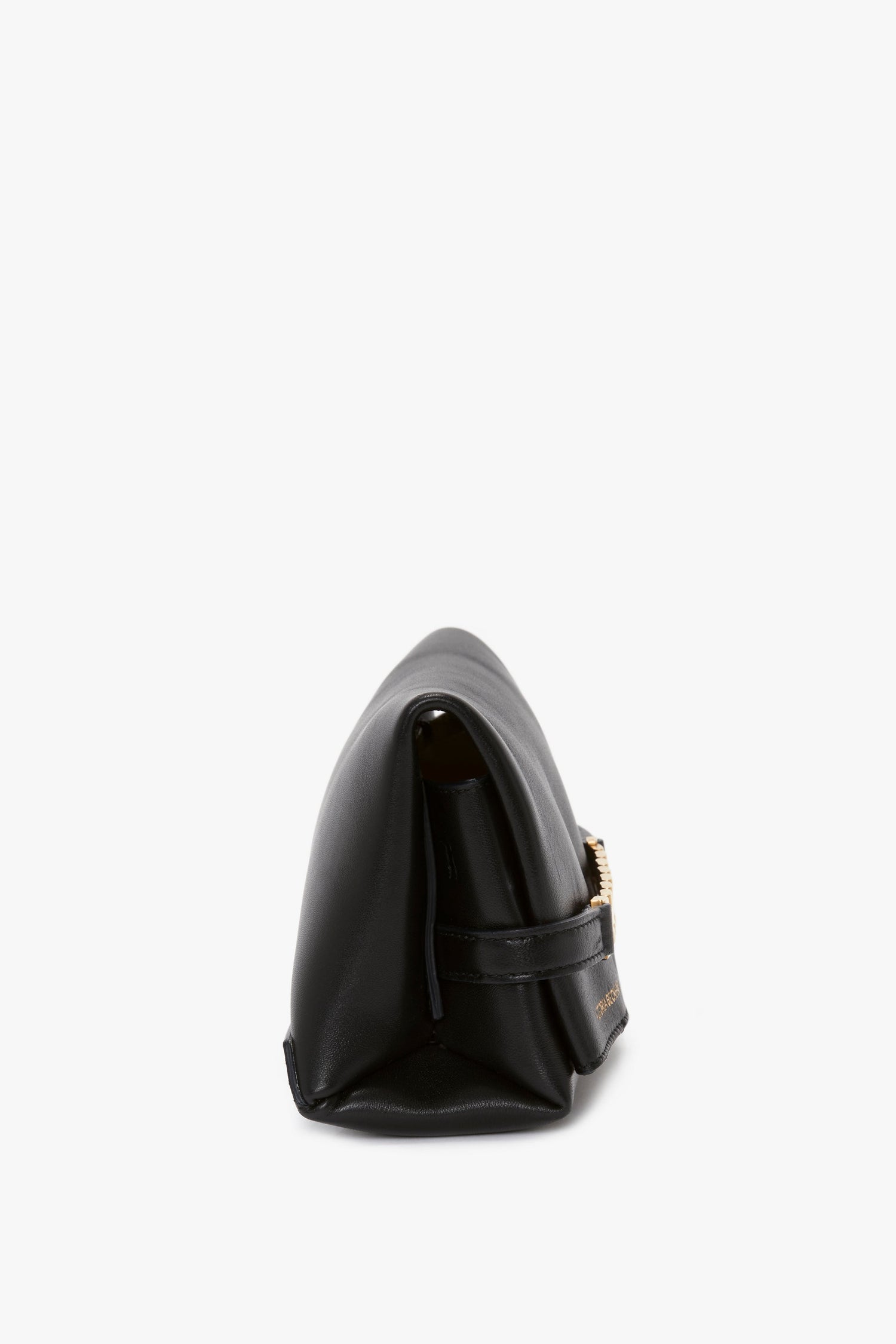 Side view of a black lambskin leather handbag showcasing its minimalist design, complemented by gold-toned hardware detail and a hint of the Mini Chain Pouch Bag With Long Strap In Black Leather by Victoria Beckham.